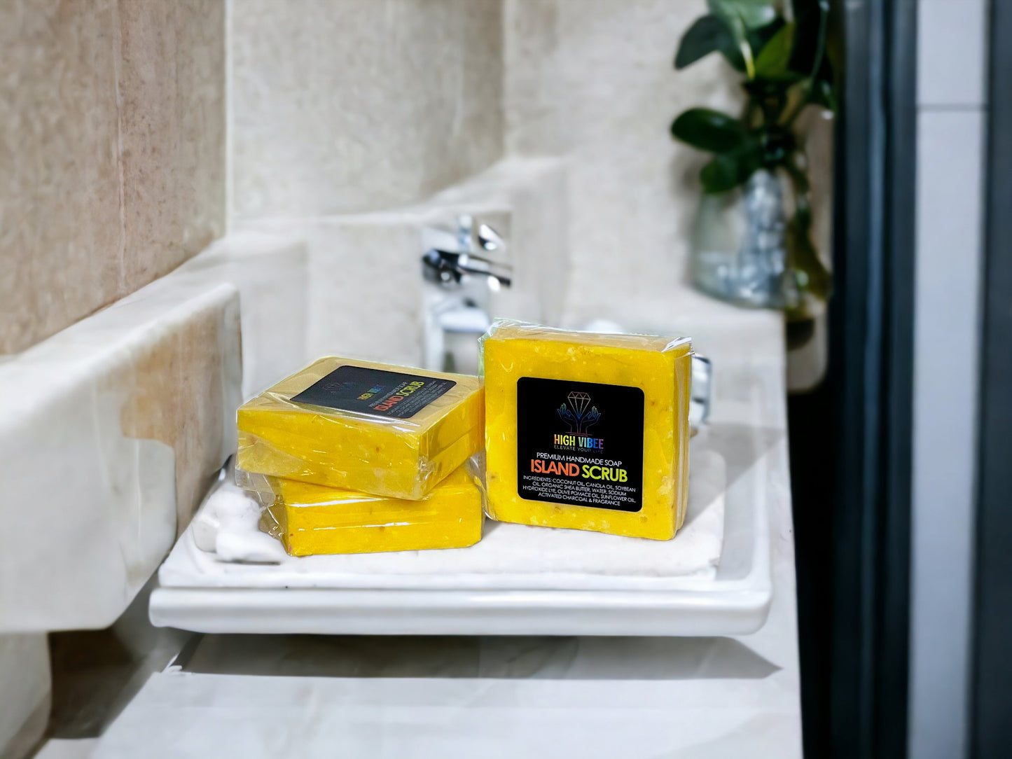 In the photo, there is the “Island Scrub” High Vibee Soap. The soap is a bright yellow. The photo shows three of these soaps on top of a cloth on a beautiful bathroom counter.