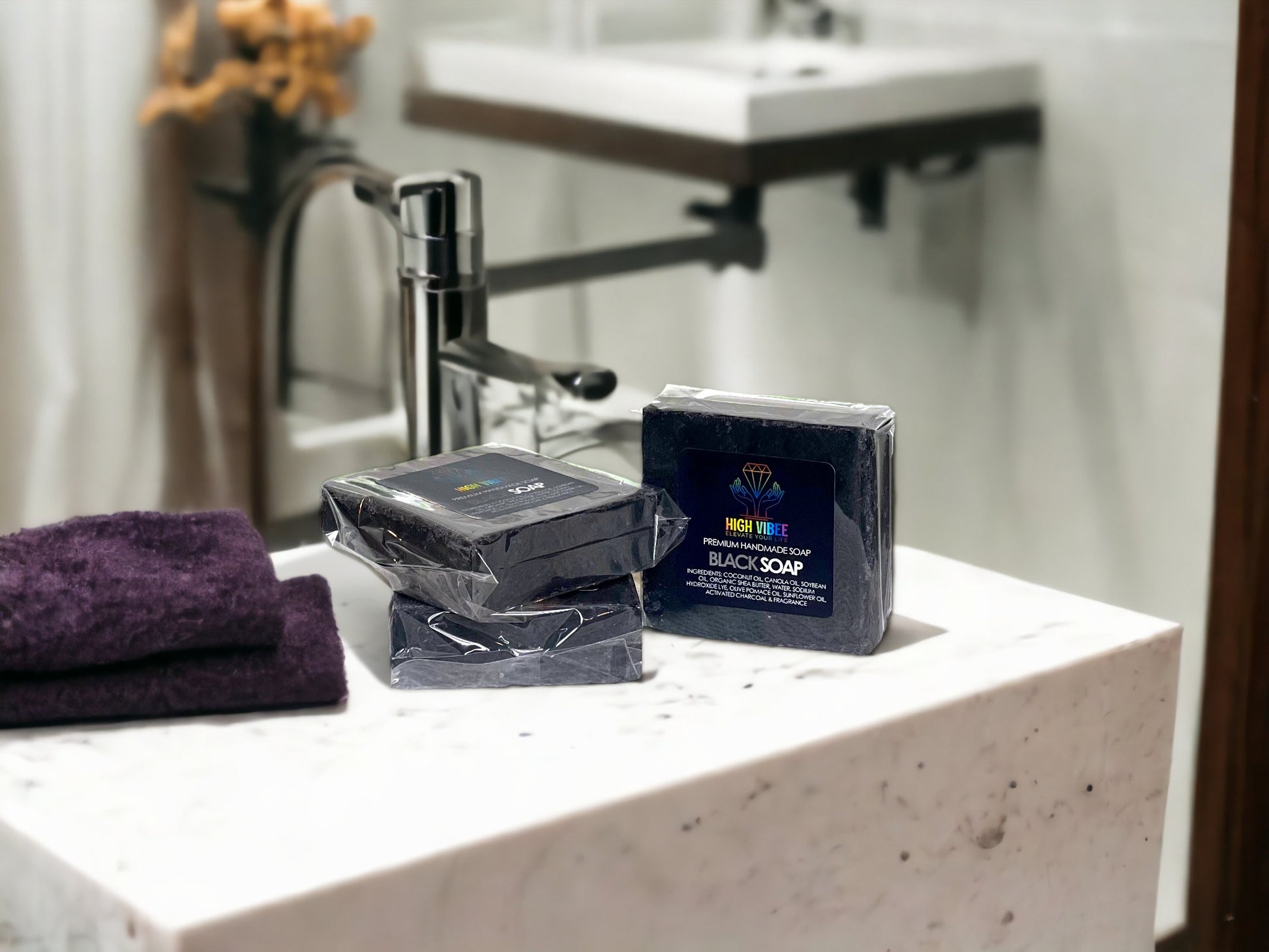 In the photo, It features High Vibee's "Black Soap". The soap is a charcoal black. The photo shows three of these soaps resting on a beautiful bathroom counter.