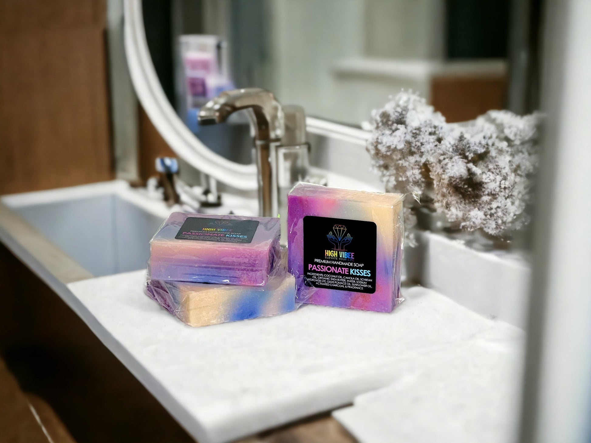 In the photo, there is the “Passionate Kisses” High Vibee Soap. The soap is an array of colors. There are hints of pink, purple, blue and creme. The photo shows three of these soaps on top of a cloth on a beautiful bathroom counter.