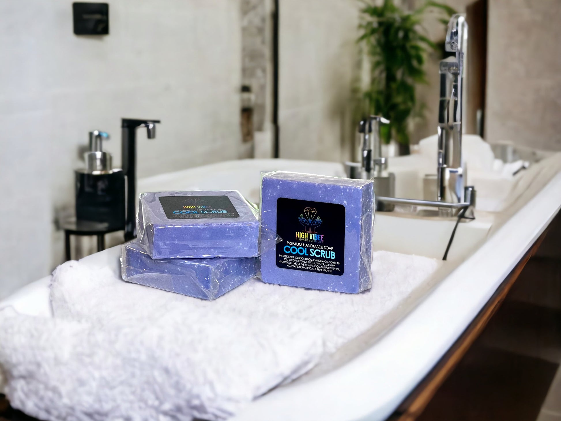 In the photo, there is the “Cool” Scrub High Vibee Soap. The soap is a light blue. The photo shows three of these soaps on top of a cloth on a beautiful bathroom counter.