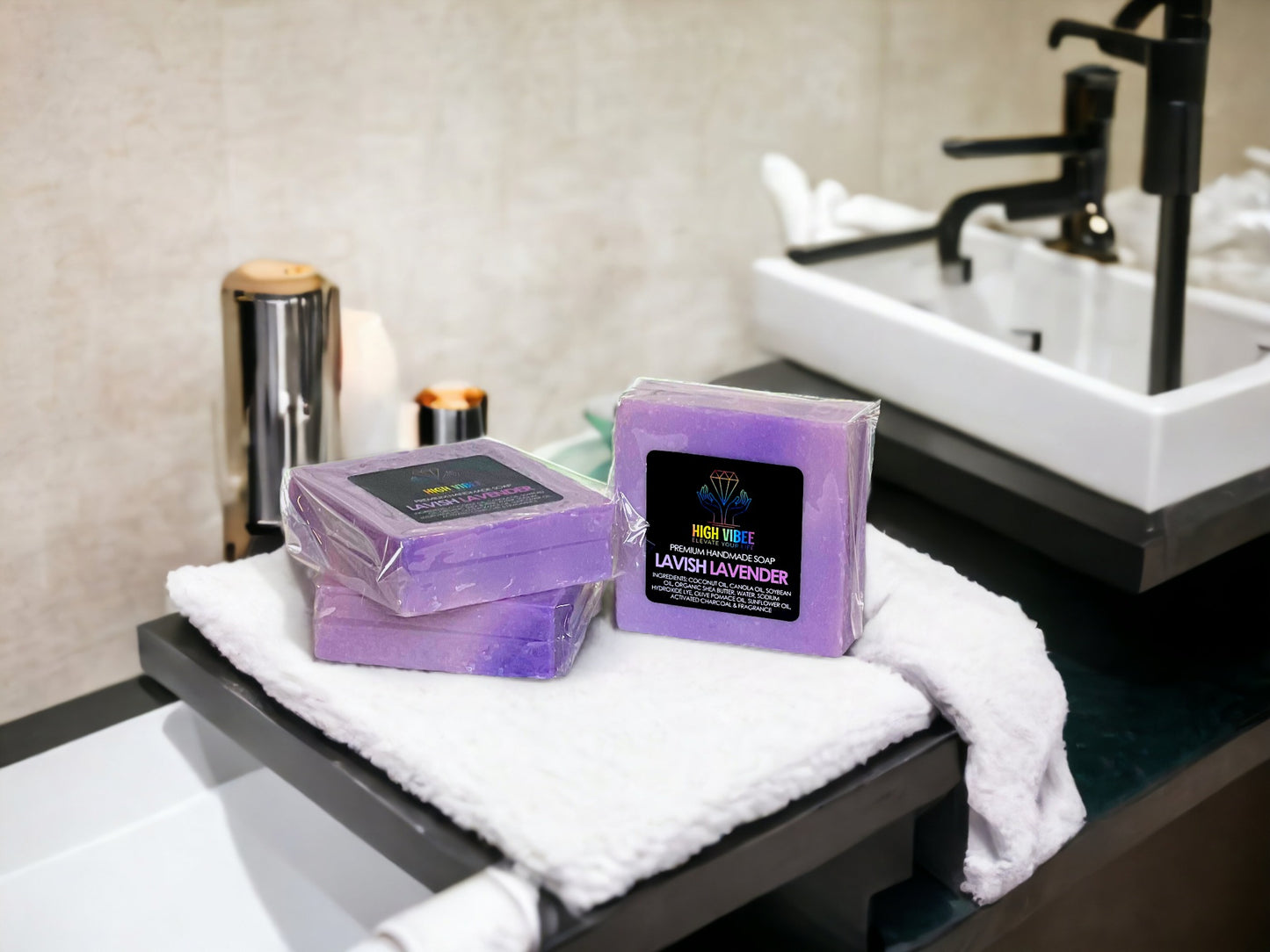 In the photo, there is the “Lavish Lavender” High Vibee Soap. The soap is a light purple. The photo shows three of these soaps on top of a cloth on a beautiful bathroom counter.