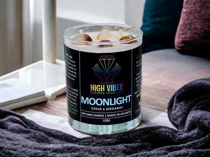 In this photo, there is a jar of High Vibee's “Moonlight” 12oz. Candle, scented with Cedar & Bergamot. In the photo, the top is off of the candle, and there are two wicks along with clear and brown crystals inside.