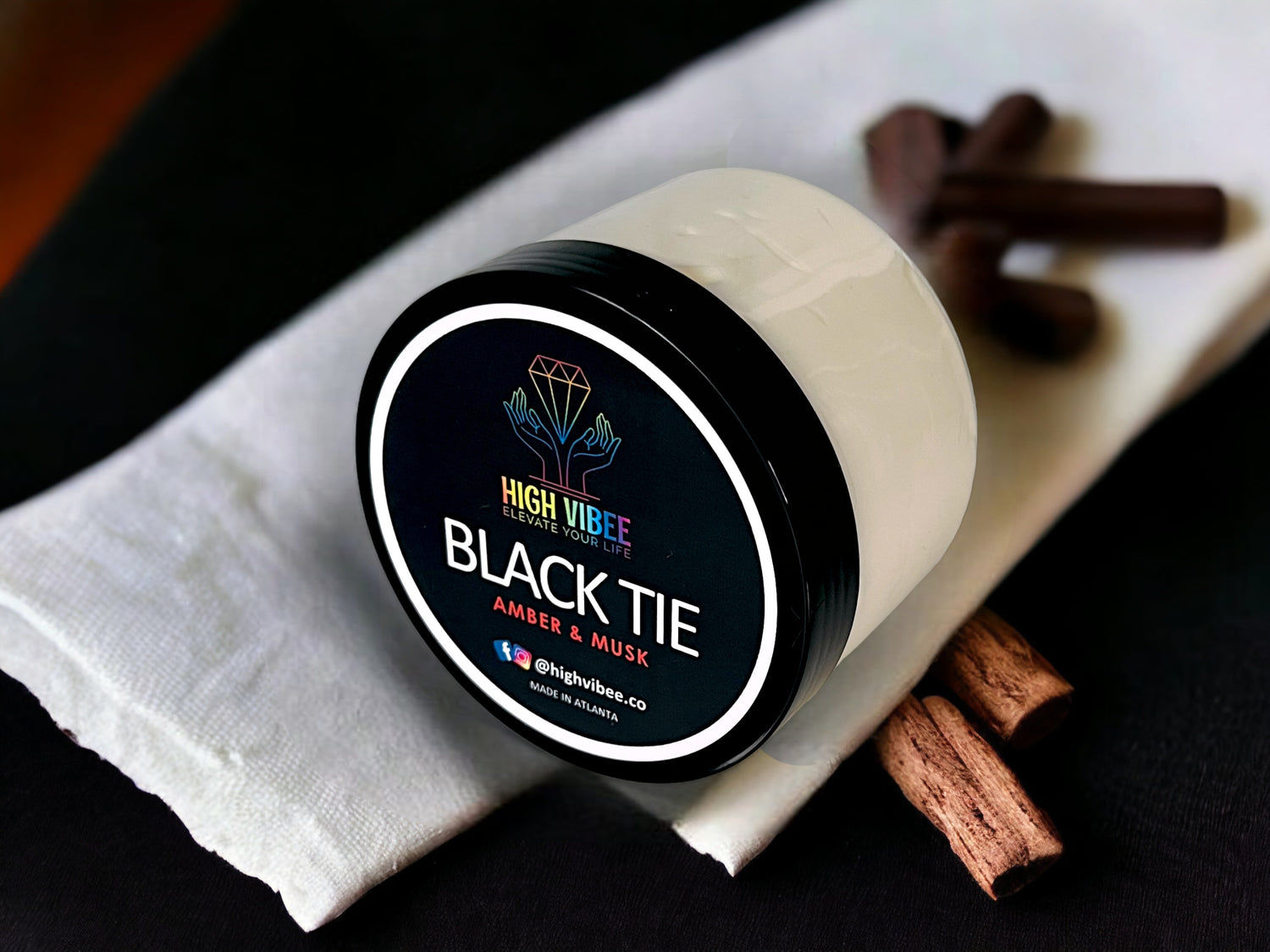 In this photo, there is a jar of High Vibee's "Black Tie" Body Butta scented with Amber & Musk.