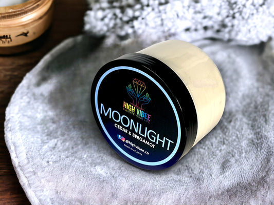 In this photo, there is a jar of High Vibee's “Moonlight” Body Butta scented with Cedar & Bergamot.